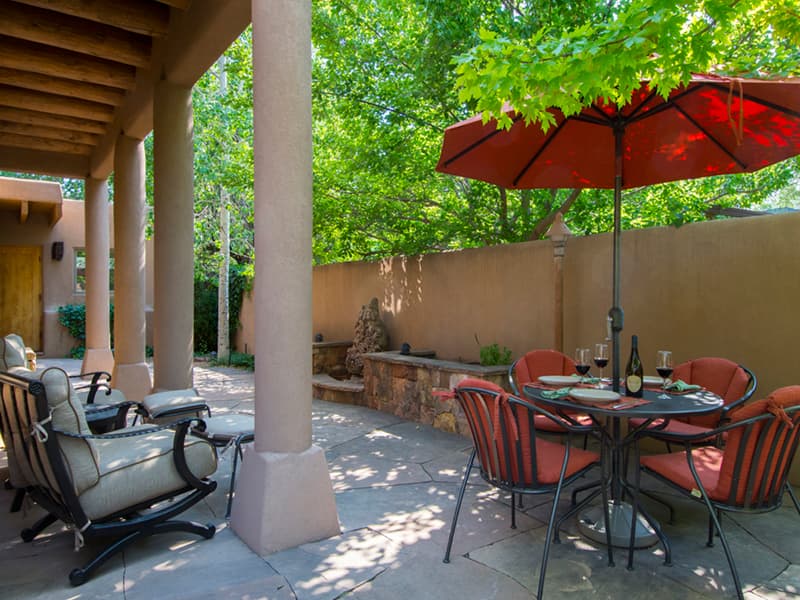 Private shaded courtyard with covered seating and a dining table beneath a red umbrella