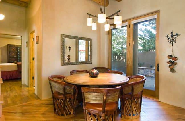 Round dining table with traditional equipale chairs beside doors opening to the patio