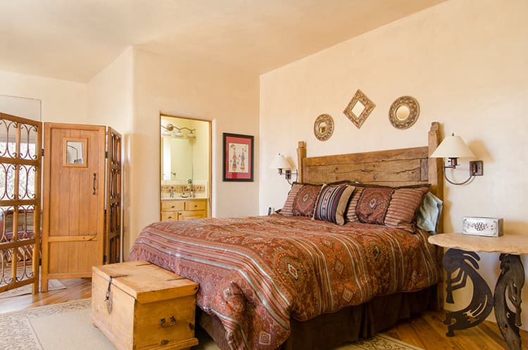 Upstairs primary bedroom with king bed, wooden headboard and adjoining bathroom