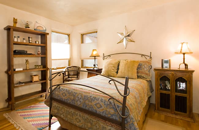 Downstairs queen bedroom with curved metal bed frame and warm Santa Fe furnishings